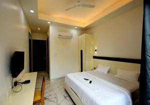 a bedroom with a bed and a desk with a phone at Hotel Prago by Green Deer Varanasi in Varanasi
