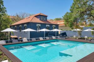 a swimming pool with chairs and umbrellas next to a building at Casa da Marechal - Boutique Hotel by Oporto Collection - Adults Only in Porto