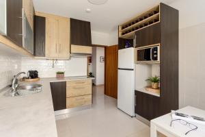 eine Küche mit Holzschränken und einem weißen Kühlschrank in der Unterkunft JOIVY Sunny apartment in Marvila in Lissabon