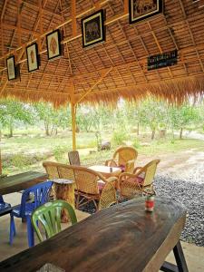 a wooden table and chairs under a straw umbrella at Kampot Camping in Kampot