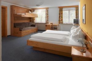 a bedroom with two beds and a couch at Tafelspitz Gruppenhaus Arlberg in Wald am Arlberg