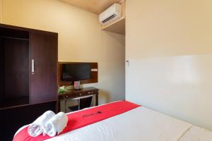 a hotel room with a bed with a red blanket at RedDoorz near Halim Perdanakusuma 3 in Jakarta +11 photos