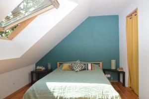 een slaapkamer met een bed met een blauwe muur bij Le charme du bois - 8 à 10 personnes- Maison entière in La Turballe