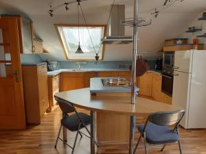 cocina con mesa, sillas y nevera en Moderne DG-Wohnung in Mainleus, en Mainleus