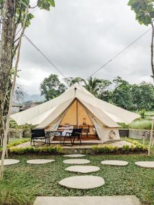 a large tent with a table and chairs in a yard at PukuPods - Tent & Cabin in Tabanan