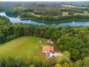 an aerial view of a house on a field next to a lake at Apartament Mazurski Rodowo in Sorkwity
