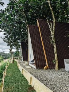 a building with a wooden facade next to trees at PukuPods - Tent & Cabin in Tabanan
