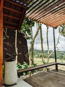 a wooden porch with a bench and a potted plant at PukuPods - Tent & Cabin in Tabanan