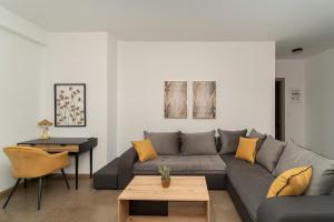 LITHOS SUITES في فينيكونتا: غرفة معيشة مع أريكة رمادية ووسائد صفراء