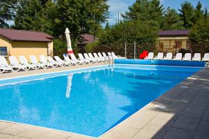 a blue swimming pool with white lounge chairs and chairs at Apartament Przy Plaży z darmowymi rowerami - by Perłowa Przystań Rent in Sianozety