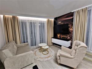 a living room with a couch and chairs and a tv at Gold Apartament in Zamość