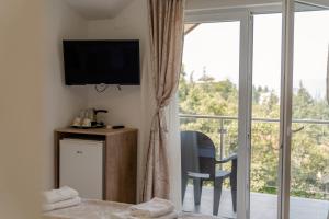 a room with a bed and a television and a balcony at DE & EV ACCOMMODATION in Ohrid