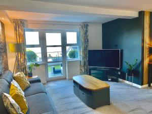 a living room with a couch and a flat screen tv at Apartment 3 Benllech with Sea views in Benllech
