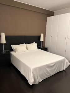 a bedroom with a large white bed with two lamps at Casas de Luanda GH-Alvalade in Luanda