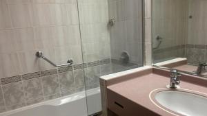 een badkamer met een wastafel, een spiegel en een bad bij SUN & SANDS HOTEL LLC in Dubai