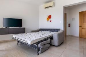 uma cama de hospital num quarto com uma televisão de ecrã plano em New top floor apartment enjoy opening views em San Ġwann