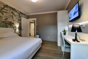 1 dormitorio con 1 cama, escritorio y TV en Hotel Residence Esplanade en Viareggio