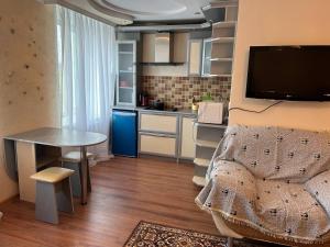 Уютная квартира Н.Абдирова 32 في كاراغاندي: مطبخ صغير مع طاولة وطاولة صغيرة وغرفة
