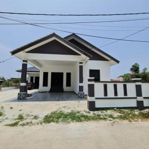 una pequeña casa blanca con techo negro en HOMESTAY CIK PHIA, en Kuala Terengganu