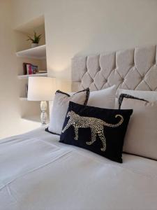 un letto bianco con un cuscino leopardato sopra di 3 Bed House with HOT TUB & 2 Bed Cottage nr Loch Ness a Inverness