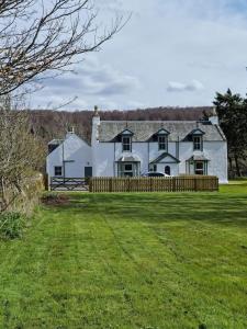 una grande casa bianca con una recinzione in un campo di 3 Bed House with HOT TUB & 2 Bed Cottage nr Loch Ness a Inverness