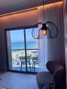 a living room with a chandelier and a view of the ocean at Suite on the beach in Haifa