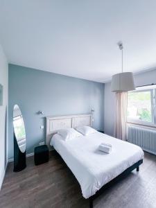 Un dormitorio con una gran cama blanca y una ventana en Les Gîtes de la Mère Michèle, en Katzenthal