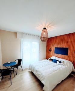 a bedroom with a large white bed and a table at Traezh ar vag - Appartement Plage Perros-Guirec in Perros-Guirec