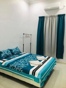 a bedroom with a bed with blue sheets and a window at HOMESTAY CIK PHIA in Kuala Terengganu