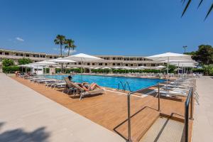 a swimming pool with people sitting in chairs and umbrellas at VOI Daniela Essentia in Conca Specchiulla