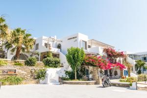 a white building with flowers in front of it at Porto Bello Tinos in Agios Ioannis