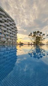 a pool in front of a building with a tree at Alezzi Infinity Aparthotel & Spa in Mamaia Nord