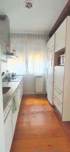 uma cozinha com armários brancos e piso em madeira em Casa Tejería. Apartamento Casco Histórico Pamplona em Pamplona