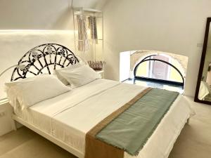 a bedroom with a large white bed with a wrought iron headboard at Ruggine Loft in Gallipoli