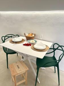 a white table with two chairs and a basket of fruit at Ruggine Loft in Gallipoli