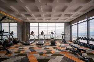 a gym with exercise equipment in a room with windows at Beach Condotel - Apec Phú Yên in Tuy Hoa