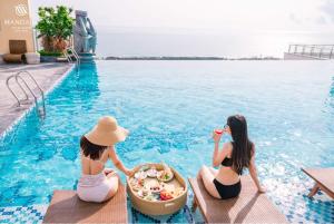 two women sitting in the water at a swimming pool at Beach Condotel - Apec Phú Yên in Tuy Hoa