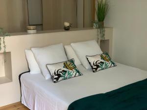 Una cama blanca con tres almohadas. en Kris Sweet Home, en Romagnat