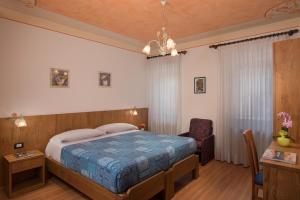 a bedroom with a bed and a desk and a chair at Hotel Centrale in Alleghe