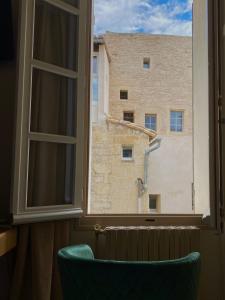 a window with a green chair looking out at a building at Hôtel du Musée in Arles