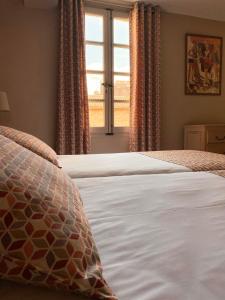 a bedroom with a white bed with a window at Hôtel du Musée in Arles