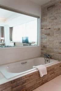 a bathroom with a large window and a bath tub at Green Hotel and Resort in Khon Kaen