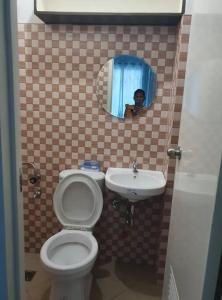 Ein Mann fotografiert ein Bad mit WC und Waschbecken in der Unterkunft Cozy 3Bedroom Home for A Big Family and Friends in Cagayan de Oro