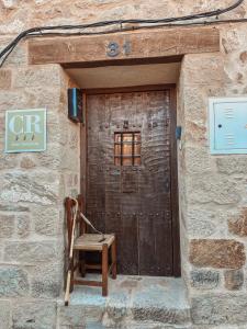 eine Holztür mit einem Stuhl vor einem Gebäude in der Unterkunft La Casa de la Acacia in Olba