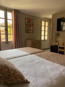 ein Schlafzimmer mit zwei Betten, einem Schreibtisch und einem Fenster in der Unterkunft Hôtel du Musée in Arles