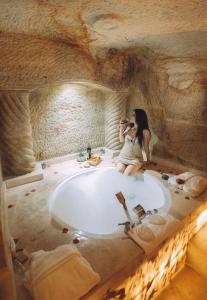 於爾居普的住宿－Tale Cave İnn，一位女性在洞穴里拍一张浴缸的照片