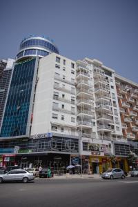 446 Luxury Apartament Center في شكودر: مبنى كبير فيه سيارات تقف امامه
