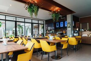 a restaurant with yellow chairs and tables and windows at Green Hotel and Resort in Khon Kaen