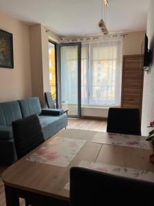 a living room with a blue couch and a table at Mona Sun Apart in Gdynia