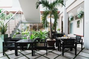 a dining room with tables and chairs and a palm tree at Green Hotel and Resort in Khon Kaen